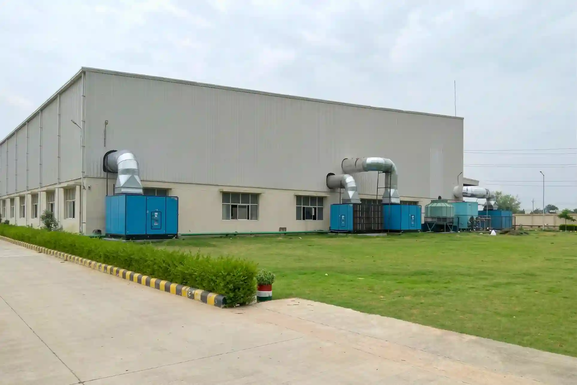 Industrial air cooling system with ducting and powertech's industrial air washer units installed outside factory building.