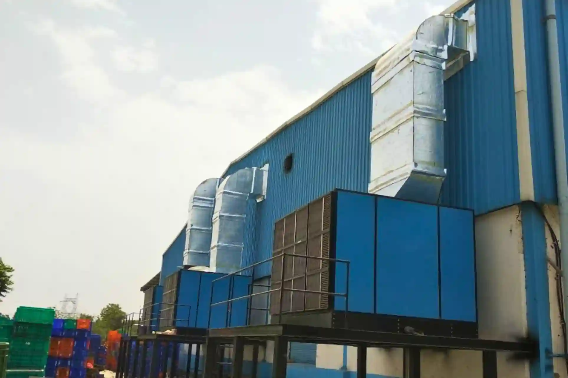 Industrial air washer units with ducting installed on factory exterior for ventilation and cooling.