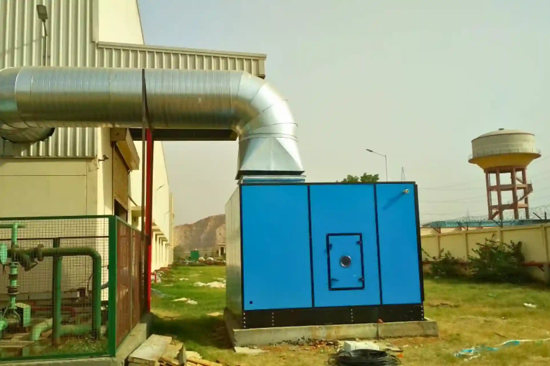 Industrial air washer unit with ducting installed outside factory building for efficient air cooling and ventilation system.