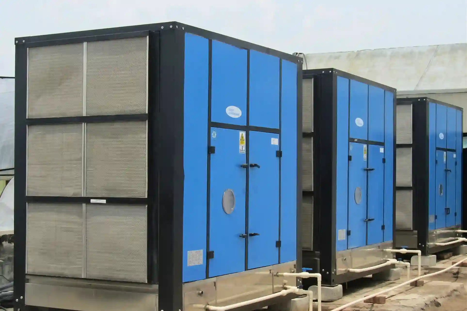 Industrial air washer units installed outdoors with filtration panels and piping for efficient factory air cooling system.