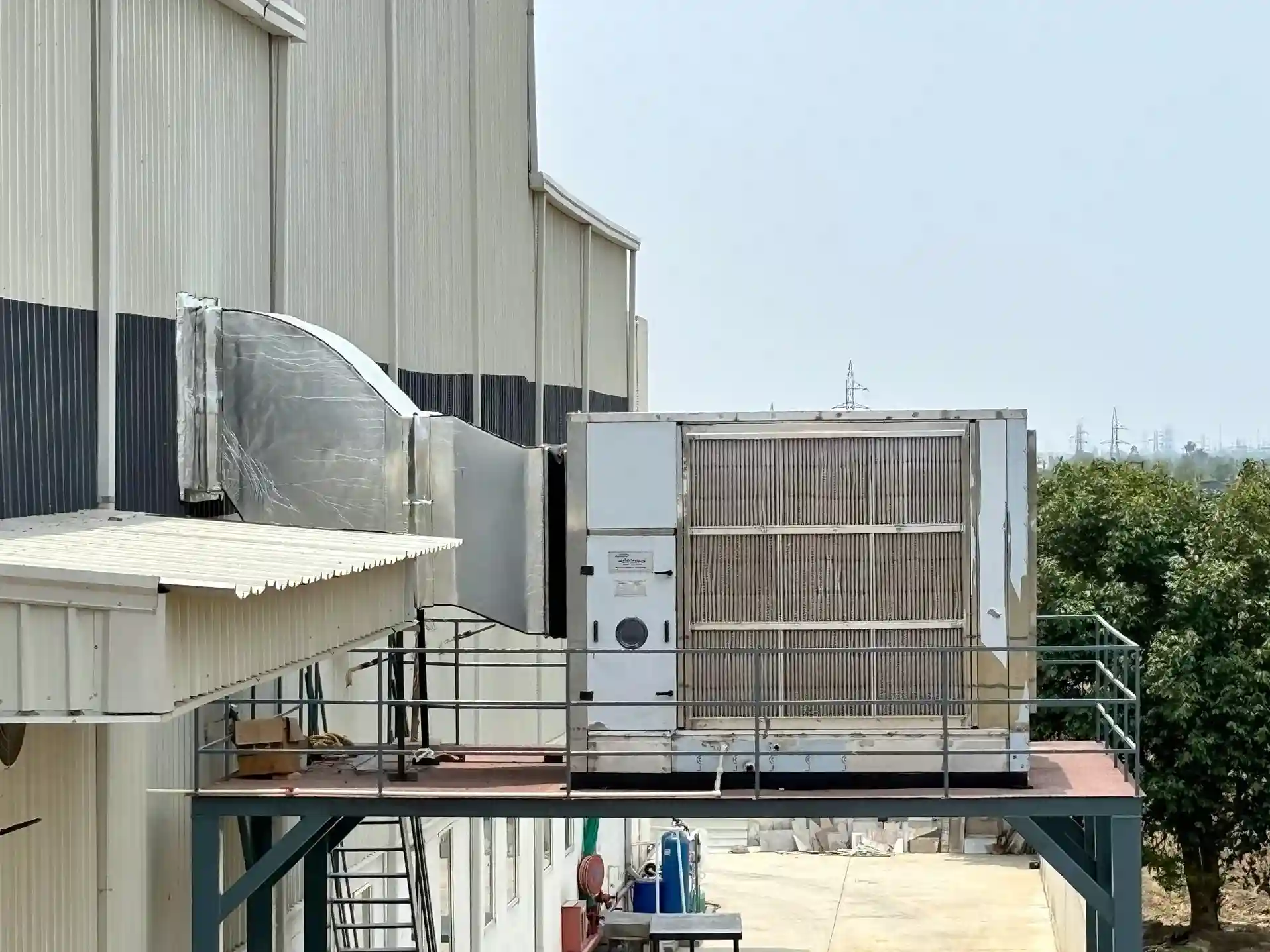 Industrial ducted air cooler with stainless steel ducting installed on factory exterior platform.