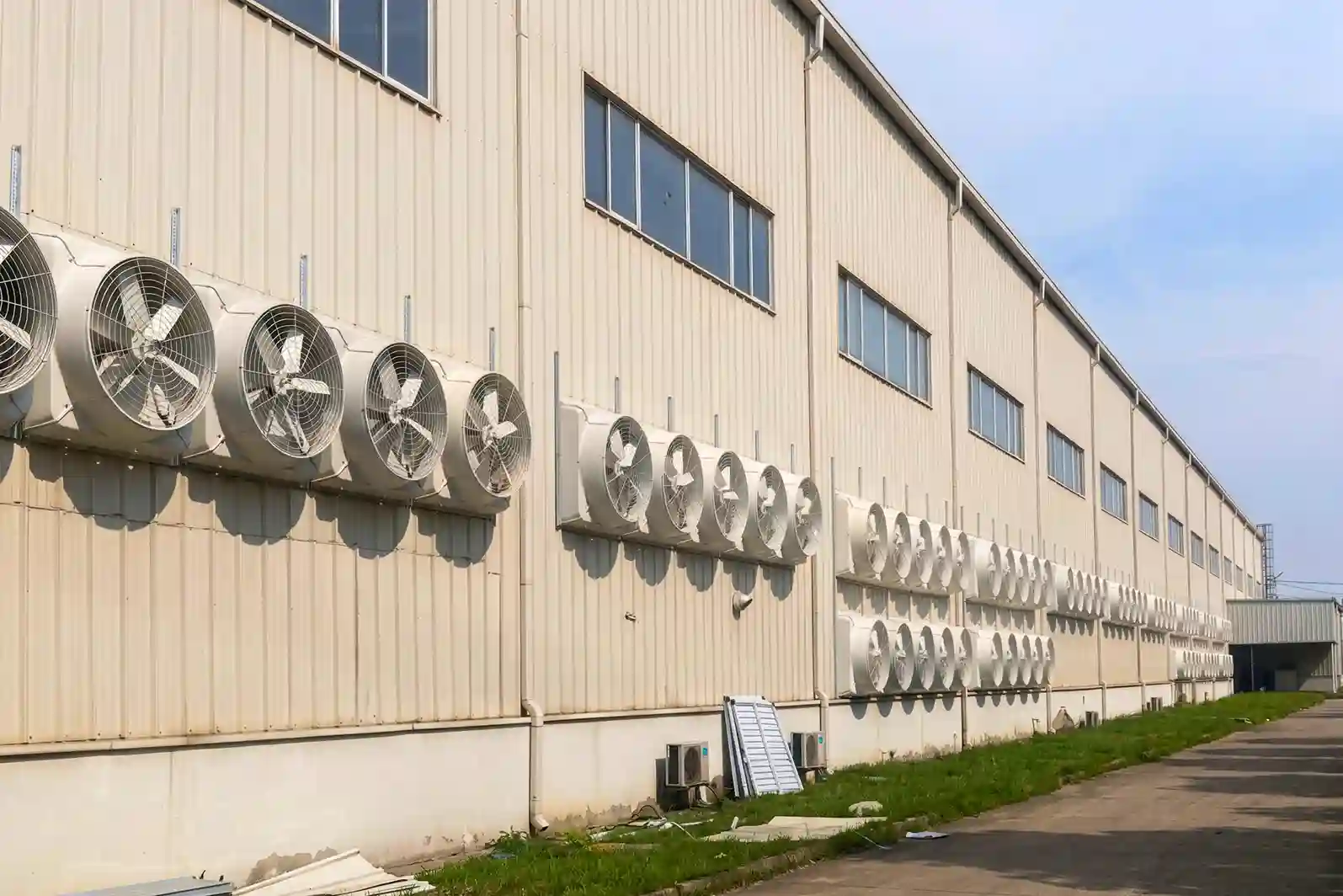 Industrial HVAC ventilation system with multiple exhaust fans installed on factory building for large-scale cooling solutions.