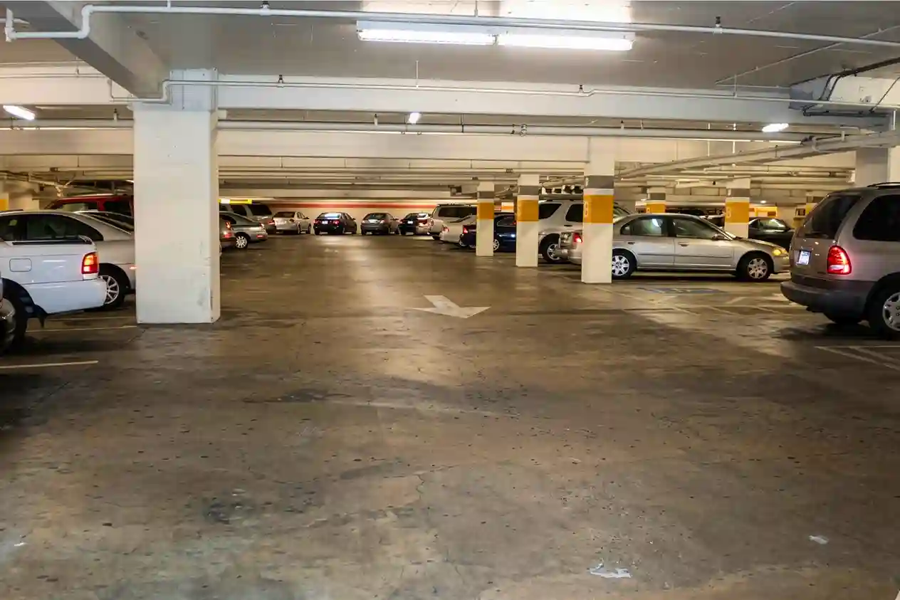 commercial basement parking lot with low ceilings and overhead ducting for air circulation.