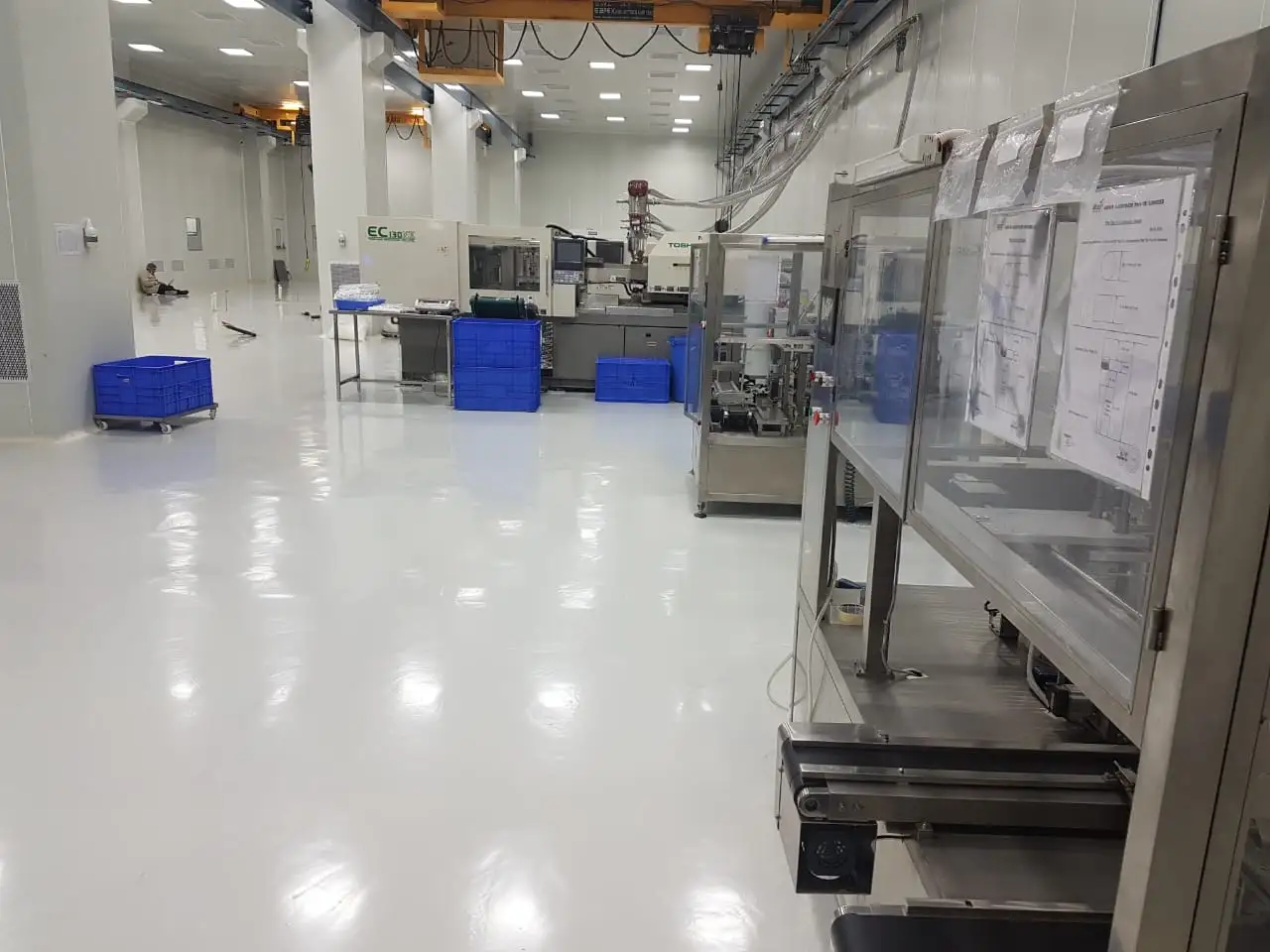 Interior view of a high-tech ISO-certified cleanroom facility featuring automated injection molding machinery and polished epoxy flooring for sterile manufacturing.