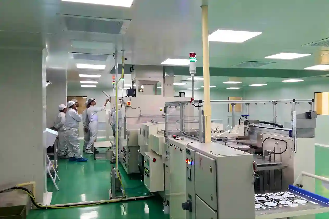 Industrial cleanroom environment showing staff monitoring automated quality control equipment.