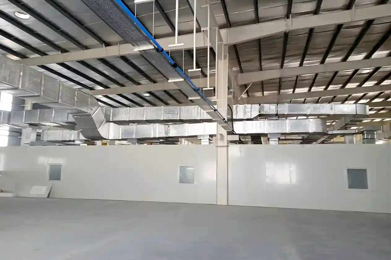 Industrial HVAC ducting system installed inside a large facility with metal air ducts, ventilation pipes, and cleanroom partition walls for efficient airflow management.