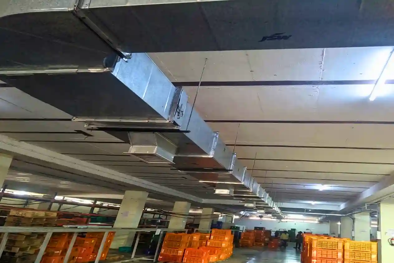 Industrial galvanized steel HVAC ductwork system installed along the ceiling of a large warehouse